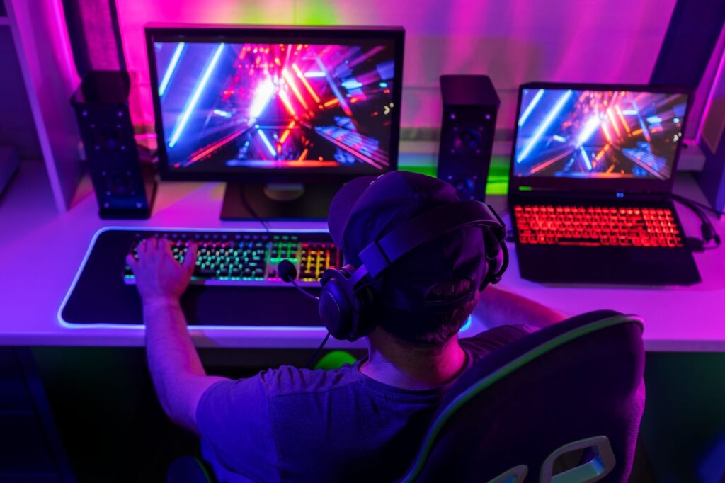 Man working on computer with multicolored neon lights
