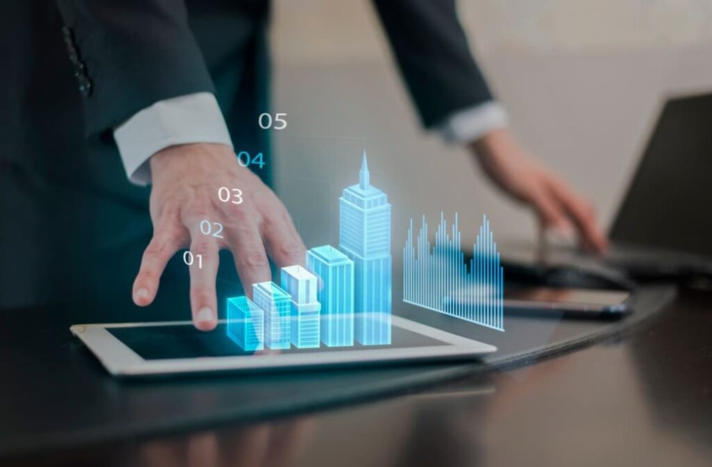 person in black clasic suit stands near the table with a tablet and digital picture of buildings 